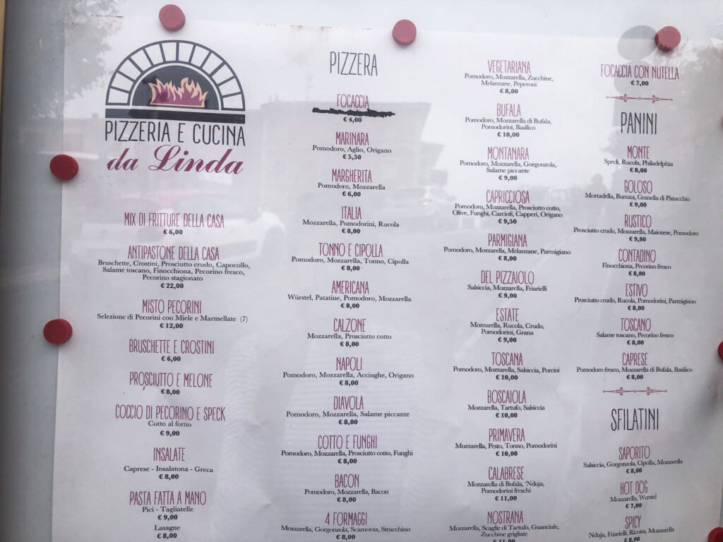 Sign in glass display showing a menu for Pizzeria da Linda in Italy.