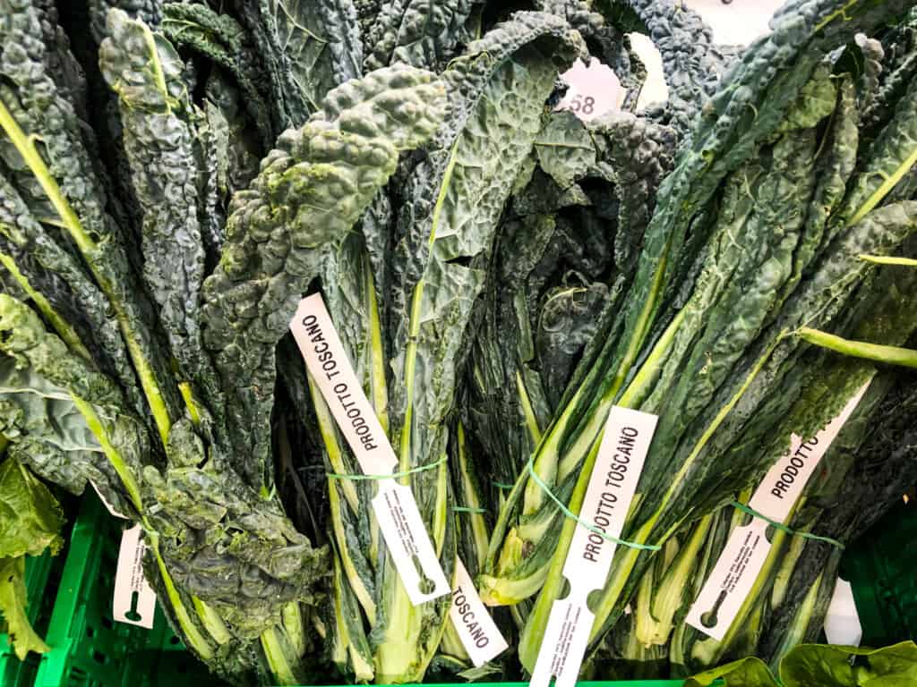 Bunches of Tuscan kale on display in a plastic market basket.