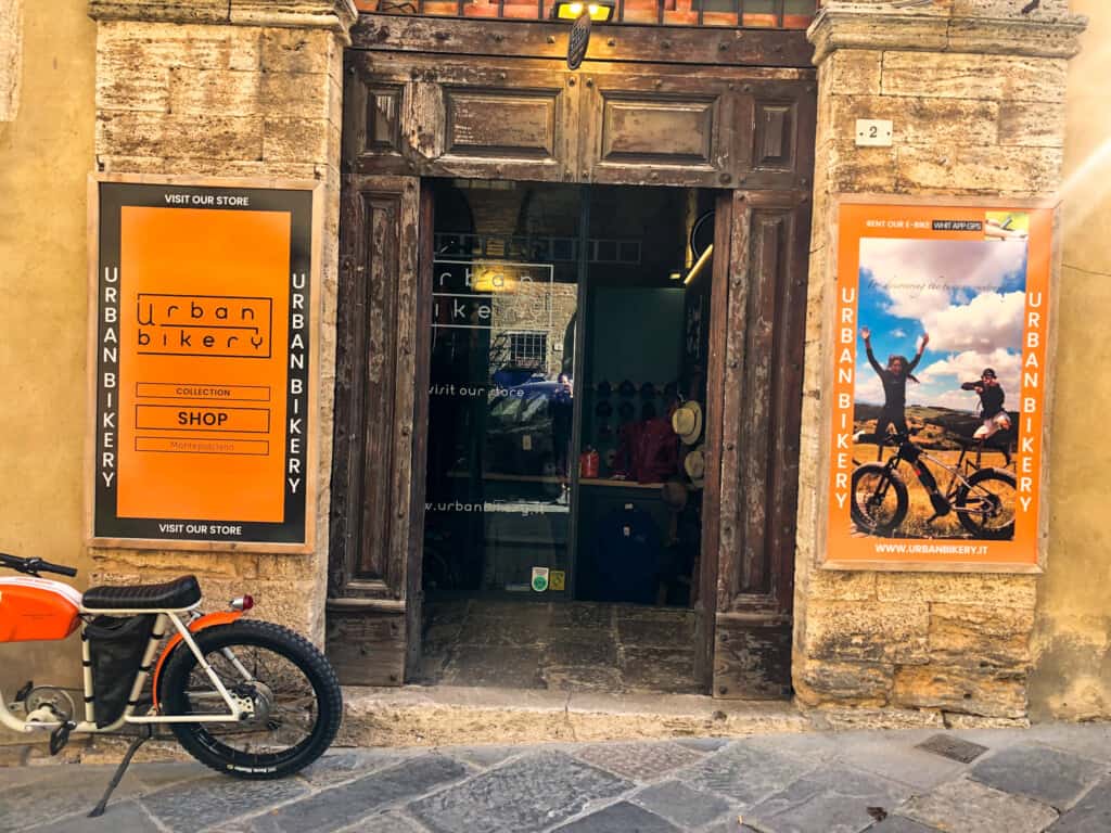 Entrance to bike rental shop in Italian village. Stone walls and wooden door. Bike to left of door.