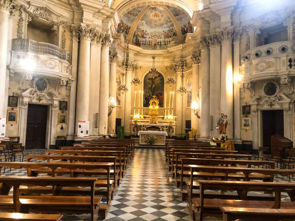 The inside of the Chiesa del Gesu in Montepulciano, Italy. You can see the pews, paintings, and the decorated ceiling.