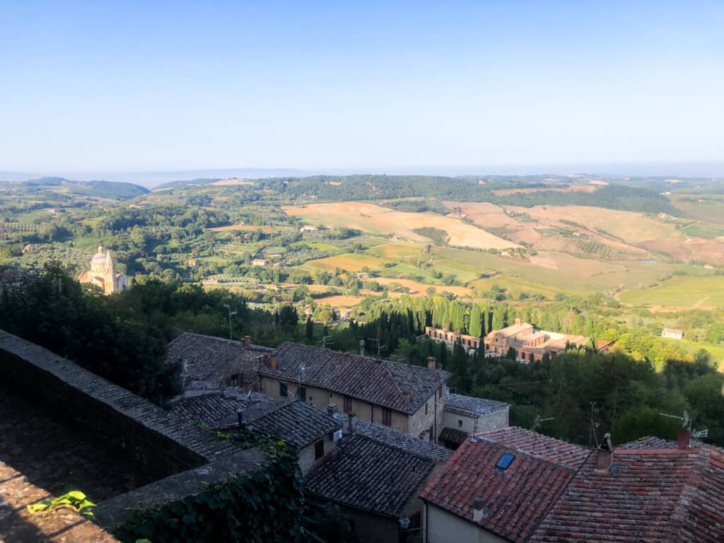 Panoramic view of Tuscan countryside from village of Montepulciano, Italy. You can see terracotta rooftops in the foreground.