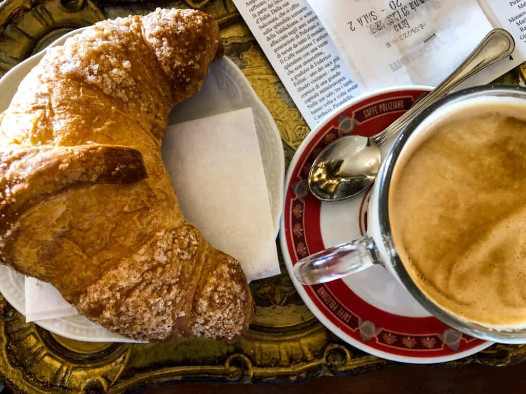 Cornetto pastry and coffee on the table at Bar Poliziano in Montepulciano, Italy.