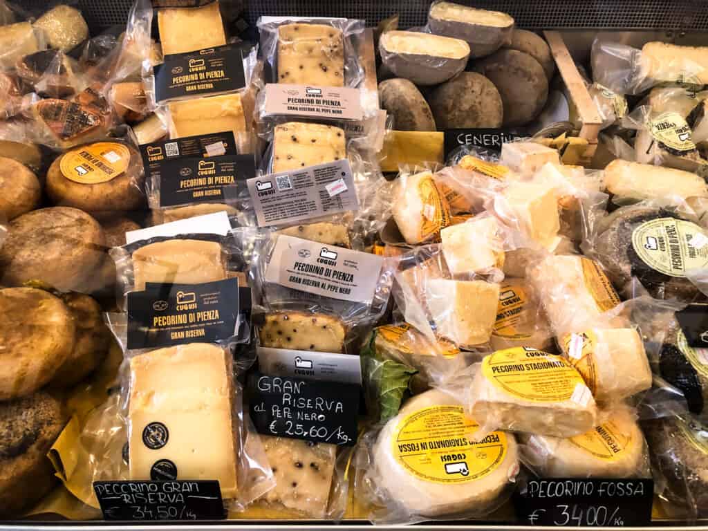Packaged cheeses on display in a refrigerated area in a cheese shop in Tuscany.