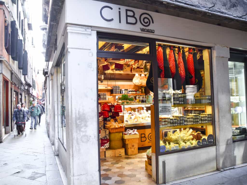 Corner shop entrance to Cibo and its food souvenirs like jarred food, prosciutto, cheeses, and more inside.