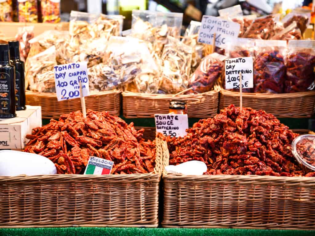 Piles of sundried tomatoes for sale at outdoor market in Italy.