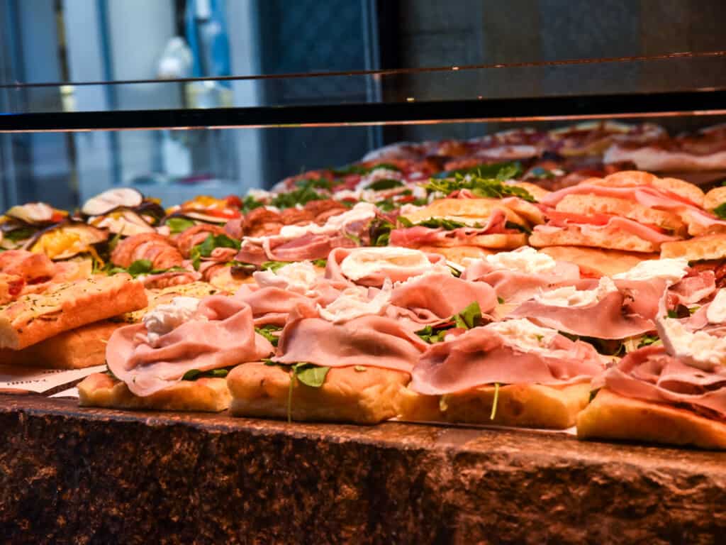 Panini and pizza in glass display from side view.