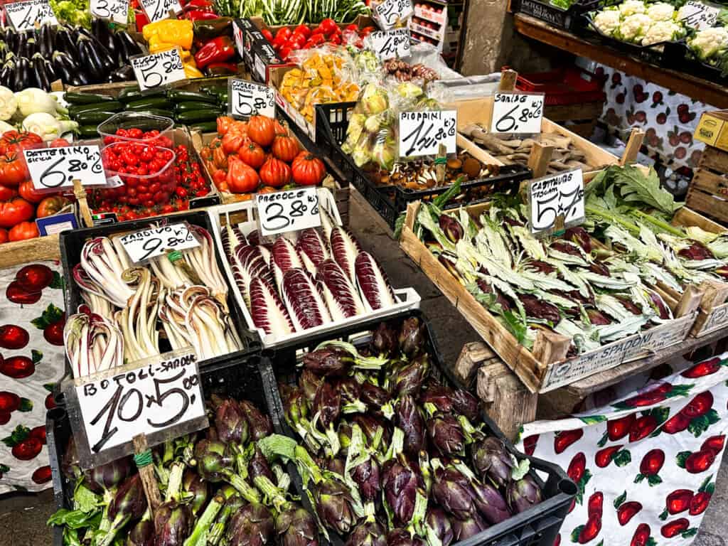 Colorful display of fresh vegetables with prices at the Rialto Market in Venice, Italy.