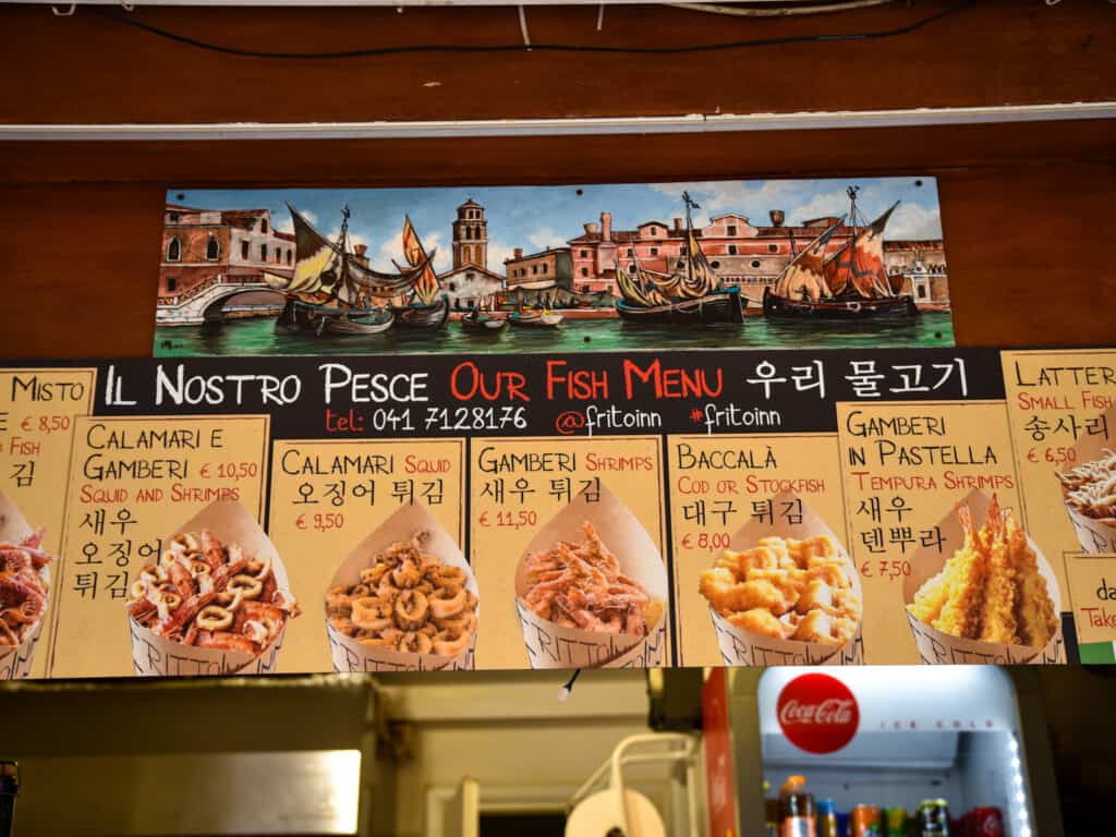 Menu on wall with photos of fried fish.