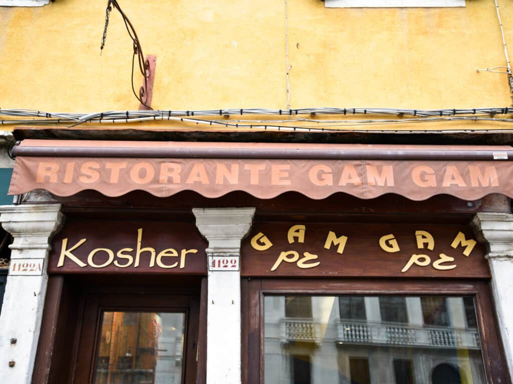 Red awning hangs above entrance and sign for Gam Gam restaurant in Venice, Italy.