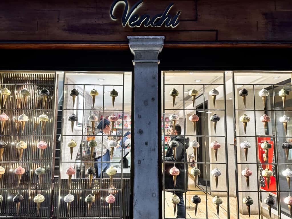 Front windows of Venchi in Venice, Italy. They're decorated with plastic cones in a grid pattern.