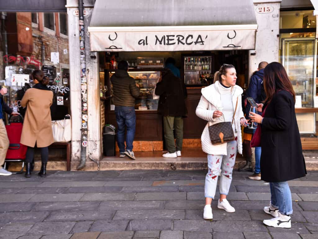 People chat and linger outside 'Al Merca' baccaro in Venice, Italy.