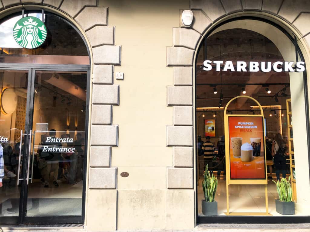 Entrance to Starbucks in Florence, Italy. Full of people ordering and drinking coffee.