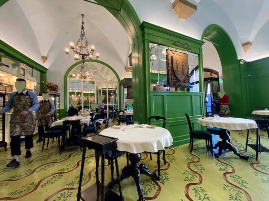 Inside Gucci Osteria in Florence, Italy. The decor is green, black, and white. There are archways and people eating and waiters wearing camouflage aprons.
