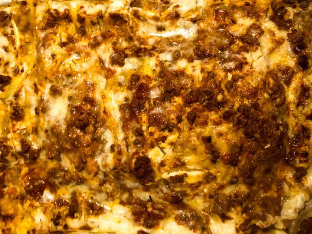 top view close up of lasagna bolognese with melted cheese and meat sauce showing through baked noodles.