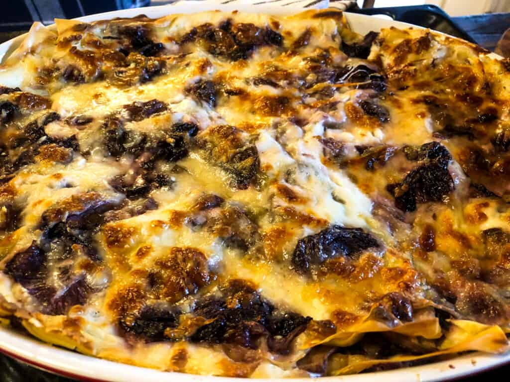 top view of a dish of baked radicchio lasagna with cheese and radicchio melted together with sheets of pasta and golden on top. 
