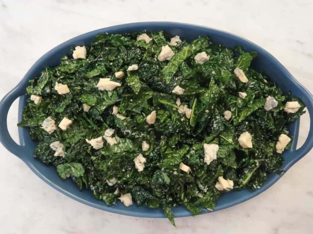 Kale salad with gorgonzola in blue dish.
