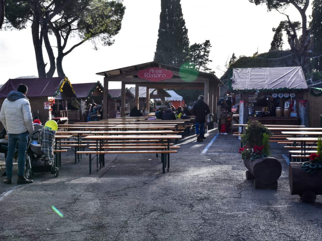 Wooden benches and wooden stalls in the outdoor food area at the Montepulciano Christmas Market.