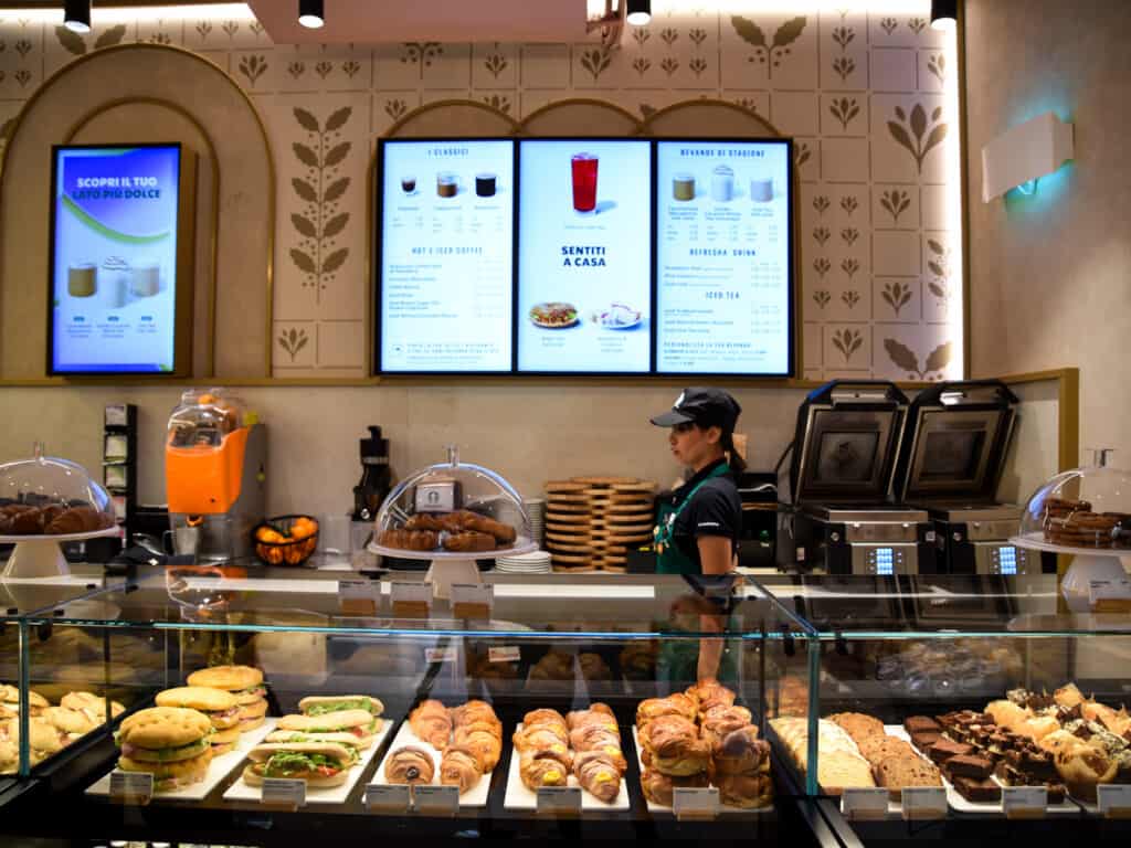 Baked goods, water, and sandwiches on display at the Starbucks counter in Italy.
