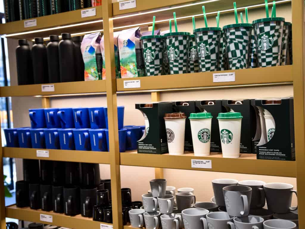 Starbucks merchandise lined up on wooden shelves for sale at Starbucks in Italy from side view. 