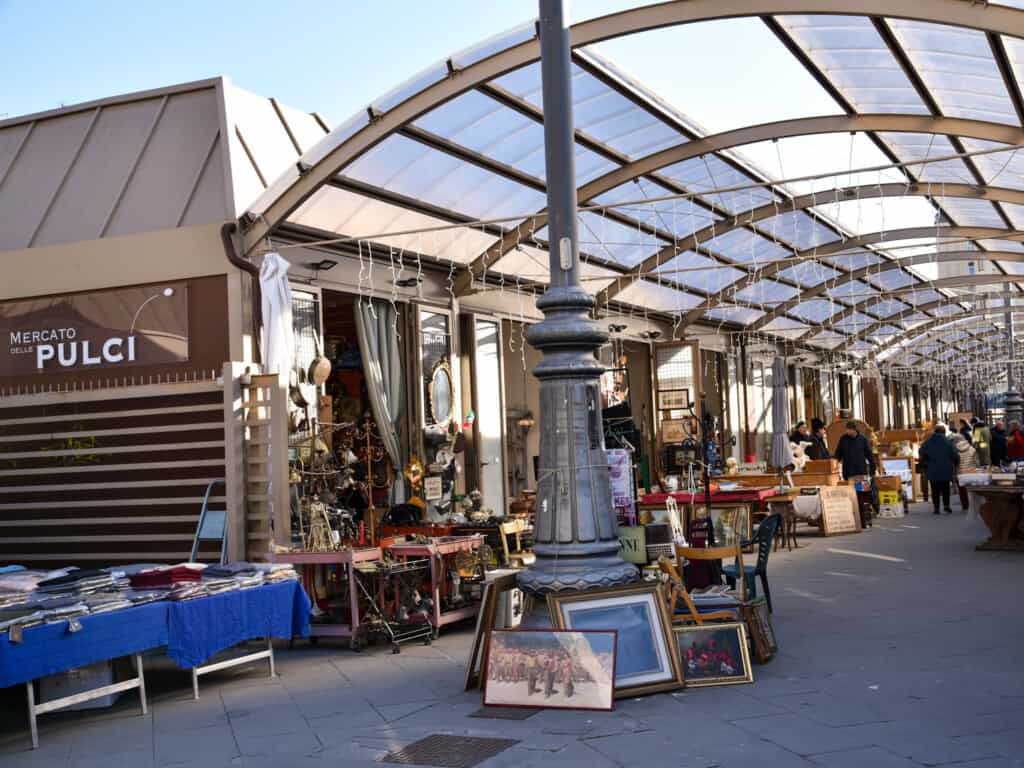 wide view of pulci market in Florence, Italy with glass covering and various objects displayed outdoors for sale. 
