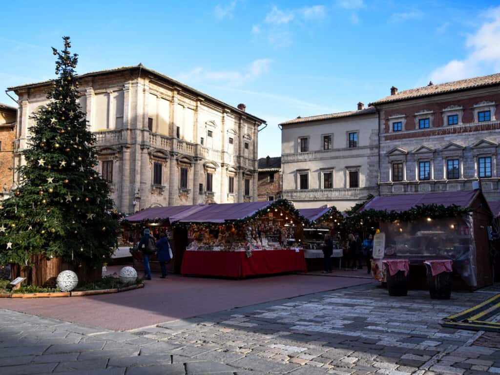Large Christmas tree and wooden stalls decorate the main piazza in Montepulciano, Italy at the Christmas Market.