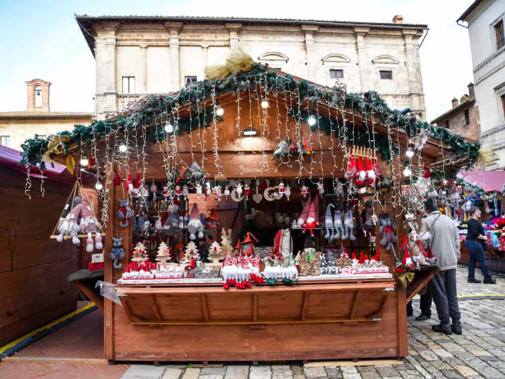 Christmas lights hang from roof of a wooden stall selling Christmas trinkets at the market in Montepulciano.