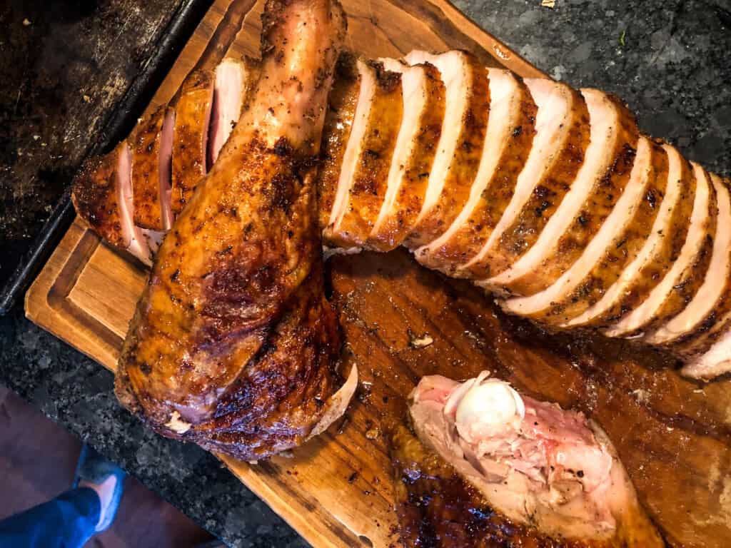 top view of roasted meat on olive oil cutting board on a dark surface from top view.