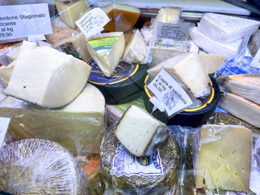 A pile of Italian cheeses wrapped in plastic, at a market in Italy.